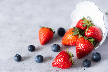 Fresh strawberries and blueberries on a gray background.