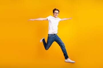 Fototapeta na wymiar Full length photo of young guy hands wings good mood fly air jump isolated over yellow color background