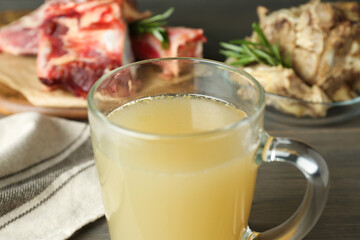 Glass cup with delicious bone broth on table, closeup