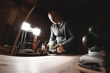 Carpenter with hand electric router machine at work