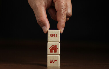 Hand stacked wooden cubes with the words BUY, SELL and house drawings. business idea real estate trading