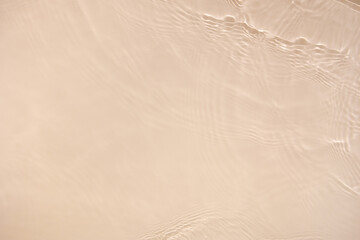 Transparent beige clear water surface texture with ripples, splashes. Abstract nature background Water waves in sunlight with copy space, top view. Cosmetic moisturizer micellar toner emulsion