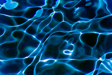 Dark blue water with sunlight reflections texture background. Ripples and glare on the swimming...