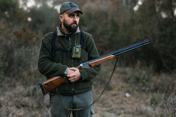 Young hunter holding his shotgun looking away