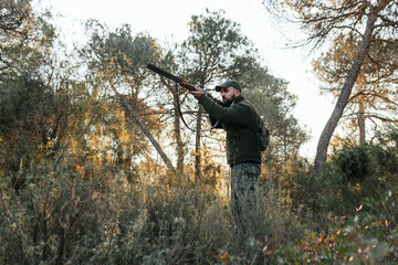 Naklejka premium Young hunter aiming with his shotgun in nature