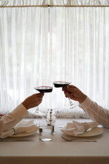 Couple with glass of red wine in a restaurant by the window
