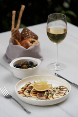 Grilled halloumi cheese and white wine glass on white table