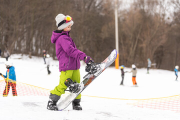 Fototapeta na wymiar Snowboard winter sport. Cute girl with snowboard going to slide in winter nature