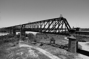Monochrome black and white elevated view of the old heritage listed Burdekin River rail bridge, a metal truss bridge,  near Charters Towers known as the Macrossan Bridge in Queensland, Australia.