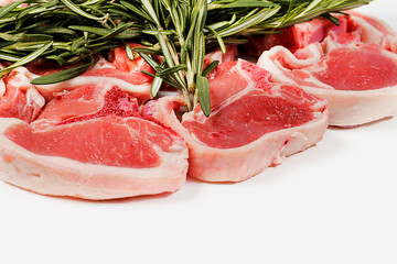 Fresh lamb chops and green rosemary herb on white background. Meat industry product. Butcher craft