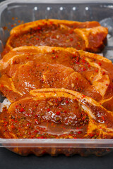 Fresh pork chops in Korean style marinade with spicy sous and herbs. Summer barbeque product in a plastic tray. Meat industry. Orient inspired flavor. Close up