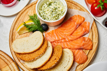 Lightly salted salmon with cheese and slices of bread on a wooden board
