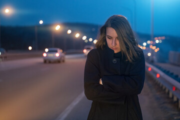Obraz premium A woman in a coat is standing near the track in a desperate state. Trouble on the road. depressive state
