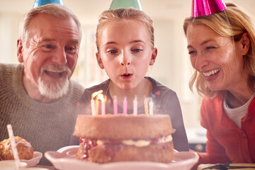 Grandparents With Granddaughter Celebrating Birthday With Party At Home Together