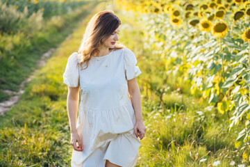 Naklejka na ściany i meble Middle age happy pregnant Woman Enjoying Summer and Walking In Sunflower Field.