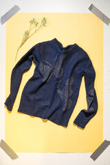 blue women's sweater on yellow background top view