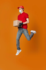 Fototapeta na wymiar Delivery man in face mask holding cardboard box and jumping