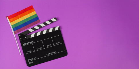 A rainbow flag and black clapperboard on purple background. LGBT CONCEPT.	