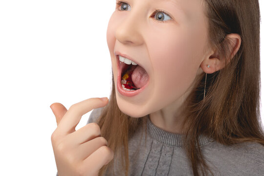 A little cute girl points to an orthodontic appliance in her mouth on her lower jaw. The concept of oral hygiene in childhood. Studio photo.