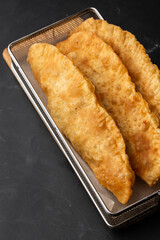 Uzbek eastern Tatar cuisine, cheburek on a black board. Cheburek - fried pie with meat. Traditional dish of Turkish and mongolian,pasties empanada