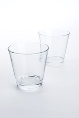 Two classic shape empty glasses on a white surface
