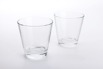 Two classic shape empty glasses on a white surface