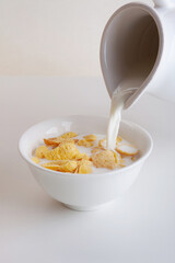 Pouring of  milk into the bowl of cornflake cereals