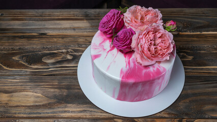 Modern red and white mousse cake with flowers on top. Wedding, festive, birthday cake on wooden background.