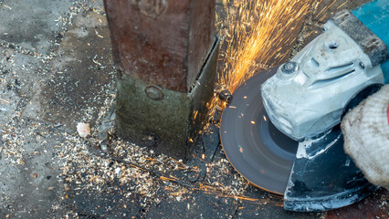 Close-up view of a worker working with angle grinder. Electric wheel grinding on steel structure. Sparks.