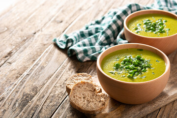 Green pea soup in a wooden bowl on rustic wooden table. Copy space