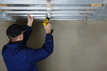Man assembles profile metal frame for plasterboard