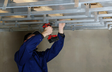 Builder installs profile metal frame for plasterboard ceilings