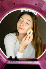 Beautiful young blogger girl touch her skin making-up.