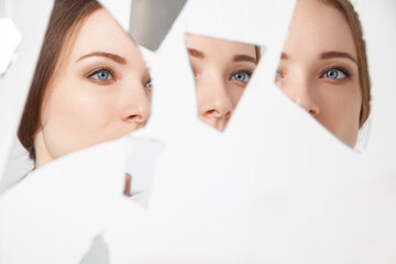 Reflection of young woman on broken mirror