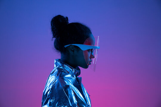 Young woman wearing futuristic smart glasses against multi-colored background