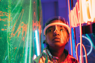 Young woman wearing smart glasses amidst illuminated neon light