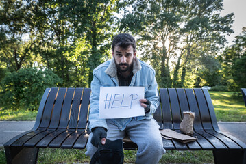 Young hungry despair ill homeless man feeling abandoned and sad sitting outdoors. Jobless sick desperate male need help. Homelessness social issues concept.