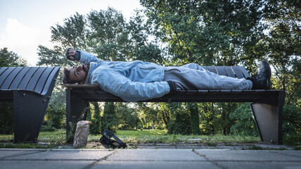 Young hungry despair ill homeless man feeling abandoned and sad sitting outdoors. Jobless sick desperate male need help. Homelessness social issues concept.