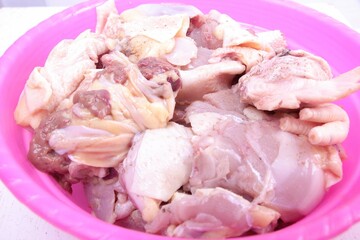 closeup, pile of chicken pieces in a pink bowl. plain white isolated