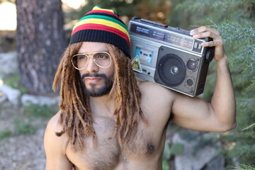 Attractive man with dreadlocks listening to music on stereo cassette player 