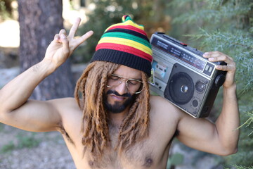 Attractive man with dreadlocks listening to music on stereo cassette player