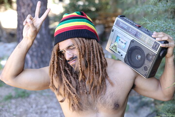 Attractive man with dreadlocks listening to music on stereo cassette player