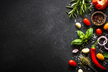 Food background on black stone table with fresh vegetables, herbs and spices. Ingredients for cooking with copy space.