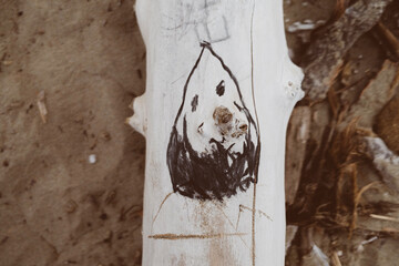 Emoticon buffa disegnata con carboncino su un tronco in spiaggia