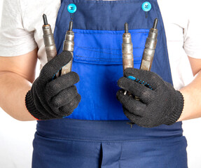 Car mechanic holds fuel car injectors in his hand. The concept of replacing and tuning the fuel system of a car at a car service.
