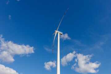 Turbina wiatrowa na tle nieba z chmurami z perspektywy poziomej z profilu.
Ekologiczne rozwiązania energetyczne źródeł odnawialnych.   