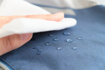 hand wipes drops of water from a cloth. Water drops on waterproof textile material. short depth of...