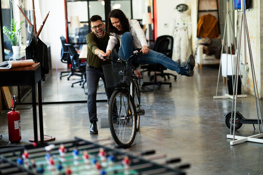 Colleagues in office. Businesswoman and businessman with bicycle. Two friends having fun together