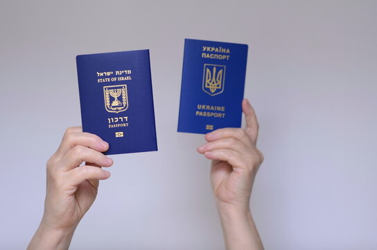 The concept of changing citizenship. Repatriation. Law of Return. Women's hands holding an Israeli passport and a Ukrainian passport on a white background