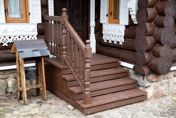 Wooden porch with steps and a door to a log cabin. Village houses architecture, close-up